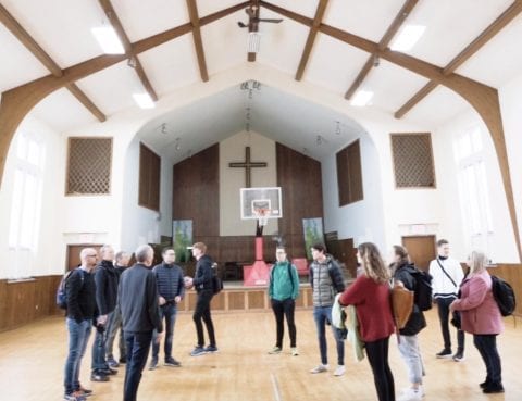 Basecamp deltakere i kirkesal med basketballbane