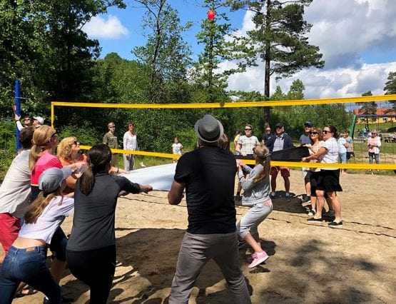 Folk som kaster vannballong over volleyball-nett